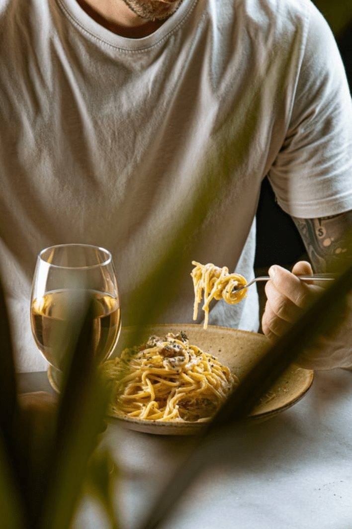 Een bord verse pasta en een glas witte wijn