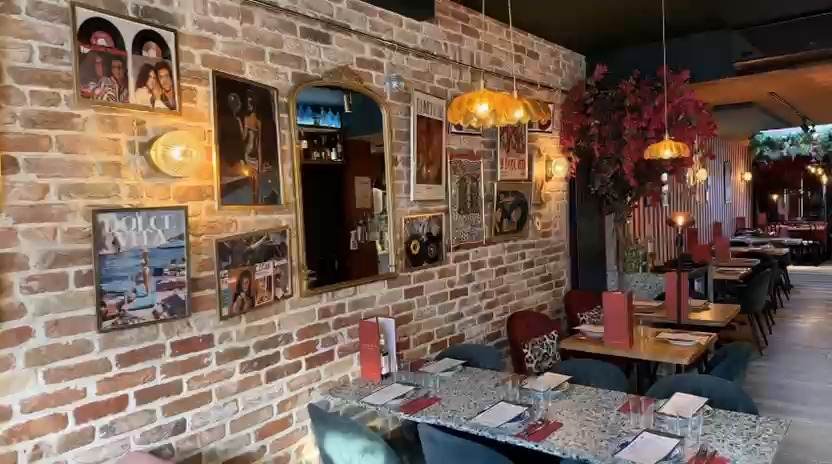 Bakstenen muur met ingelijste foto’s en spiegels in het restaurant