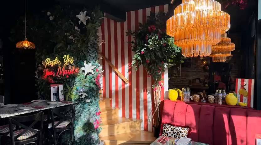 De zaal met de neon "Pasta, Yes. You, Maybe" en rood-wit gestreepte muur